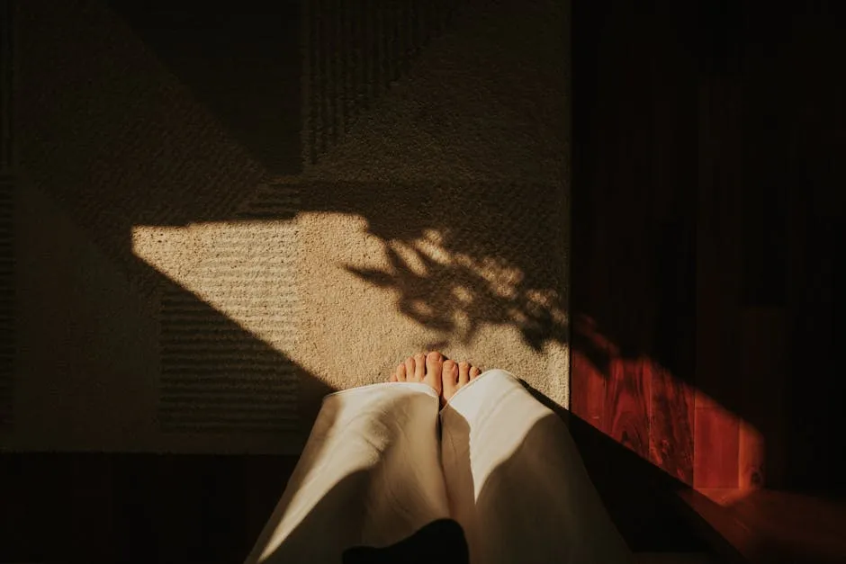 Dritë e ngrohtë e mëngjesit që hyn përmes dritares duke krijuar modele hije paqësore