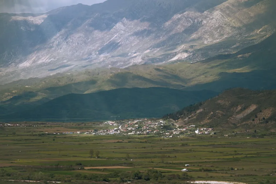 Pamje e luginës shqiptare me fshat dhe male madhështore