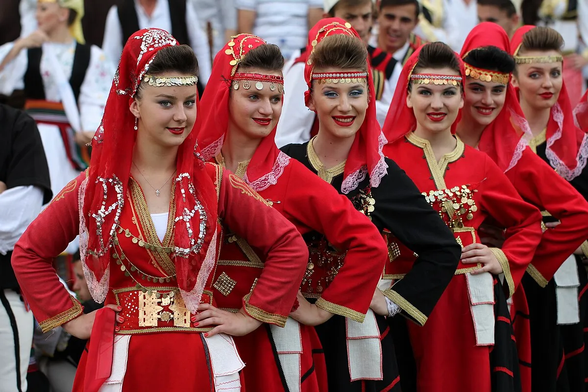 Një grup grash të reja shqiptare të veshura me kostume tradicionale, që simbolizojnë trashëgiminë kulturore dhe historike.
