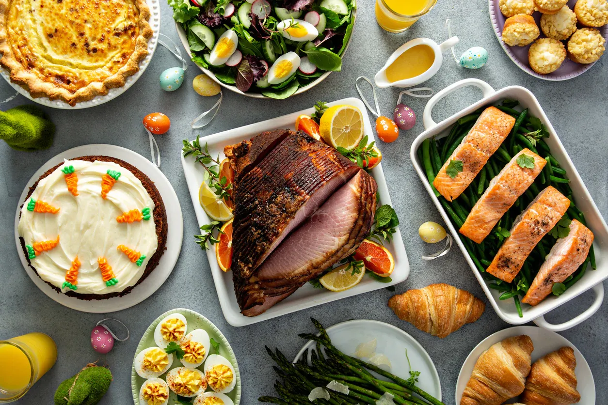Një tryezë e pasur me ushqime festive, duke përfshirë mish të pjekur, peshk, sallata dhe ëmbëlsira, që pasqyron bollëkun dhe ndryshimin e dietës moderne.